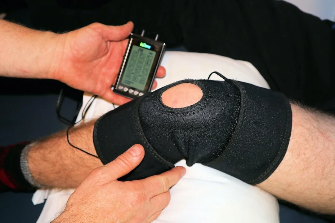 Electrical stimulation wrap on a knee with a handheld stimulator, from earlier Lawson research